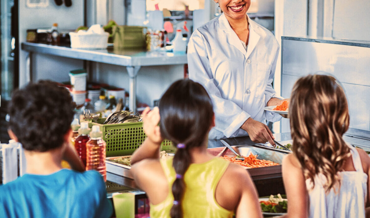 Woman serving food to schoolchildren