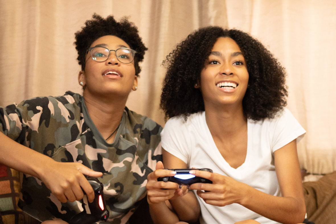 Two Teenage African American Sisters Playing Video Games at Home
