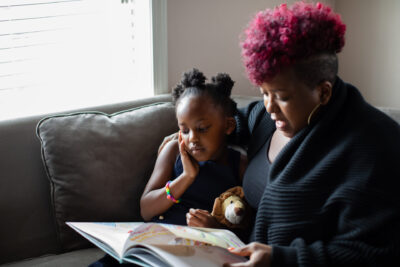 African American mother and daughter reading book together