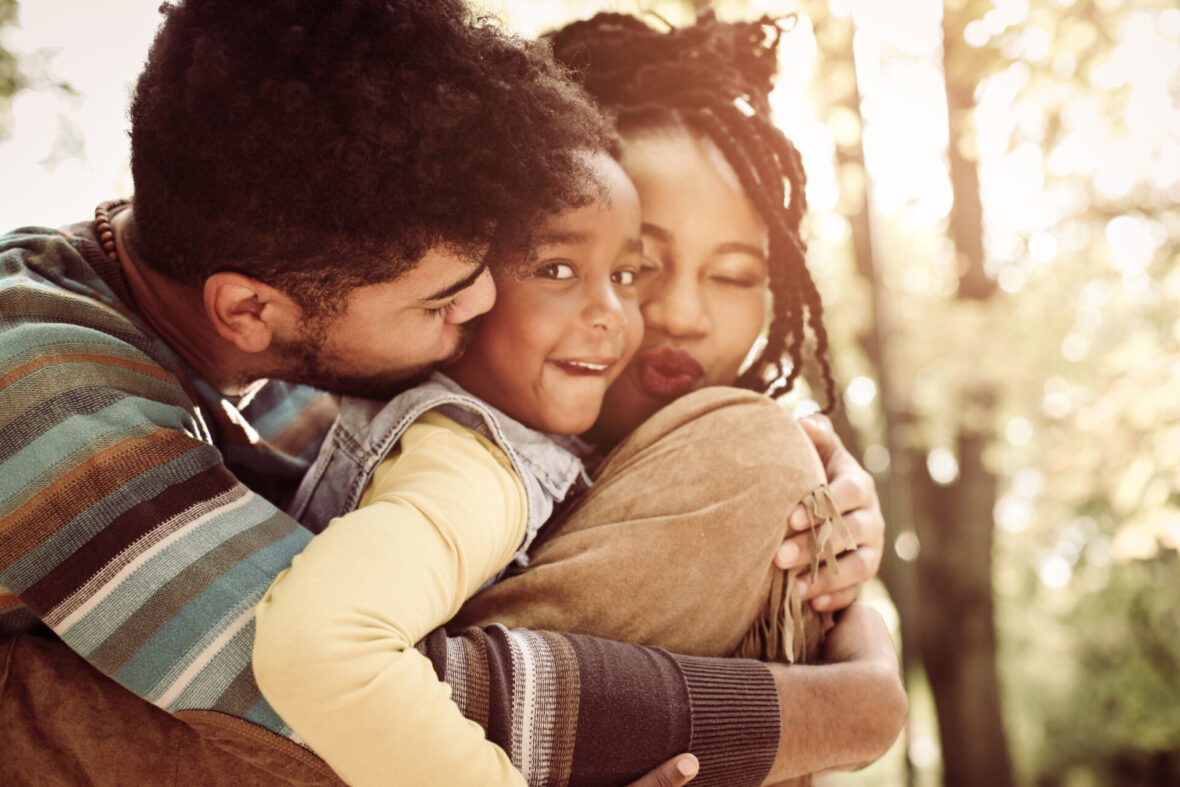 Parents hugging their little daughter.