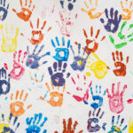 White wall with colorful multicolored hand prints.