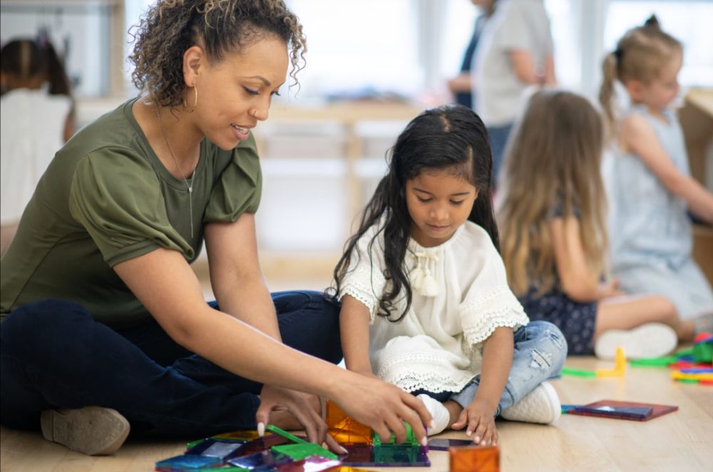 child and teacher playing on floor
