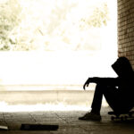 Silhouette of Lonely Teenager Sitting in the Dark Doorway