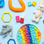 Colorful childrens toys and sensory fidget items on blue background